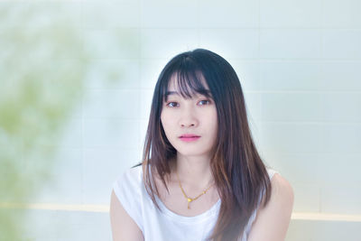 Portrait of young woman standing against wall