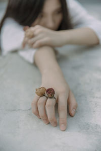 Young woman wearing rose shape rings while lying on floor