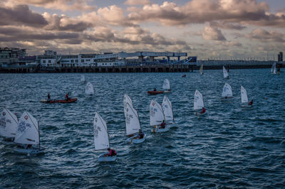 Boats in sea against cloudy sky