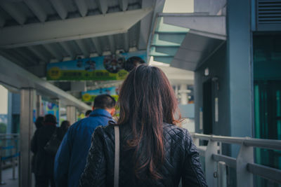 Rear view of woman walking by railing at subway station