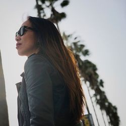 Side view of young woman standing against sky