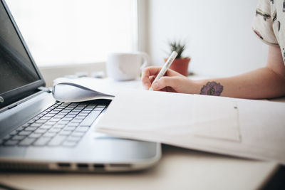 Midsection of woman using laptop on table