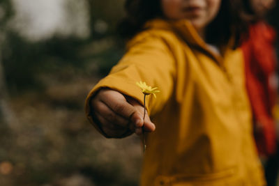 Cute child with yellow jacket holding yellow flower