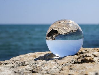 Rock on sea shore against sky