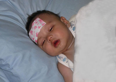 High angle view cute baby boy with bandage on forehead sleeping at home