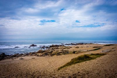 Scenic view of beach against cloudy sky