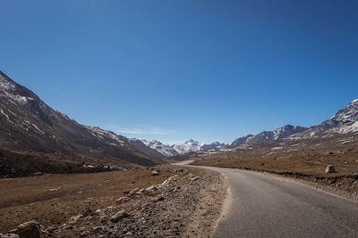 Road amidst mountains against clear blue sky