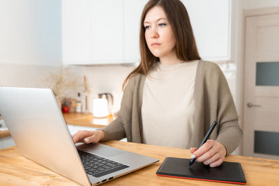 Young woman using laptop at table