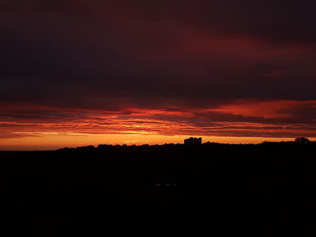 Silhouette landscape against dramatic sky during sunset