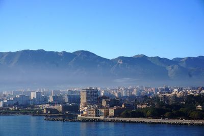 Scenic view of river and buildings against clear blue sky