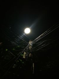 Low angle view of illuminated cables against sky at night