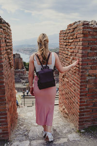 Rear view of woman standing against wall