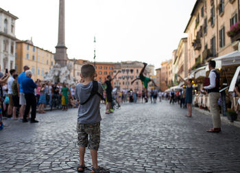 Boy standing on footpath in city