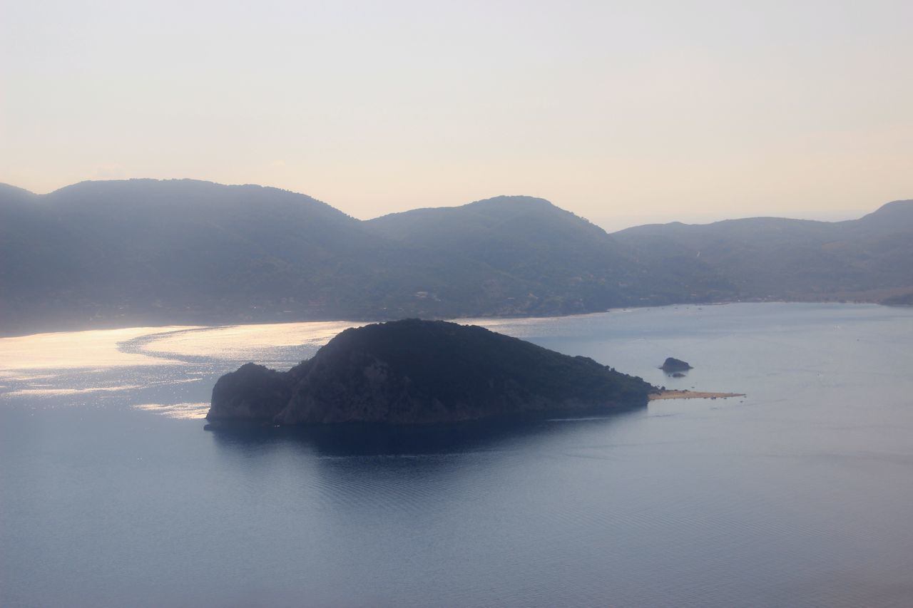 water, mountain, sea, tranquil scene, scenics, tranquility, clear sky, beauty in nature, reflection, copy space, waterfront, nature, mountain range, sunset, idyllic, rock - object, silhouette, lake, rock formation, sky