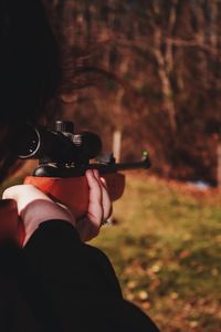 Woman shooting with rifle against trees