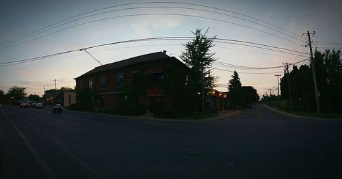 Electricity pylons on road at sunset