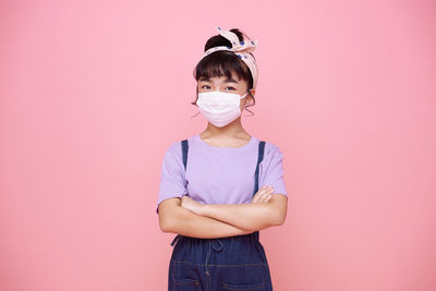 Full length portrait of woman standing against pink background