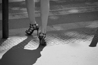 Low section of woman in heels walking on footpath