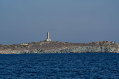 Lighthouse by sea against clear sky