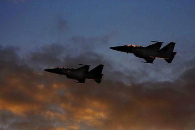 Low angle view of military airplanes flying in cloudy sky