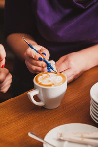 Midsection of woman holding coffee cup on table