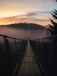 Footbridge over sea against sky during sunset