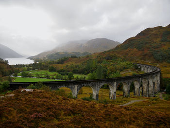 Arch bridge over mountains against sky