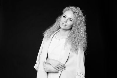Portrait of smiling woman against black background