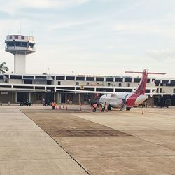 People at airport runway against sky