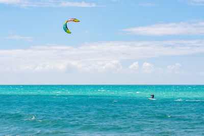View of a unrecognizable person kiteboarding on the ocean against clear sky