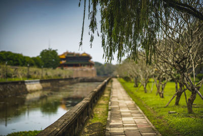 Footpath by lake against sky