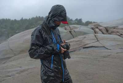 Side view of man holding umbrella while standing on land