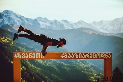 Information sign on mountain range against sky