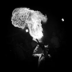 Rear view of man with arms outstretched at night