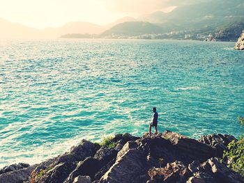 Man fishing at sea shore against sky