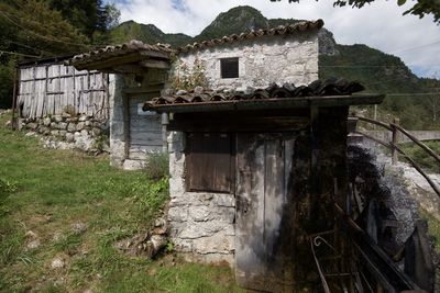 Old house on field by building against sky