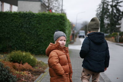 Rear view of kid standing against trees, street 