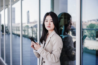 Confident beautiful chinese business woman using mobile phone in building office. technology