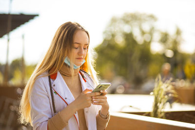 Young woman using mobile phone while sitting in cafe