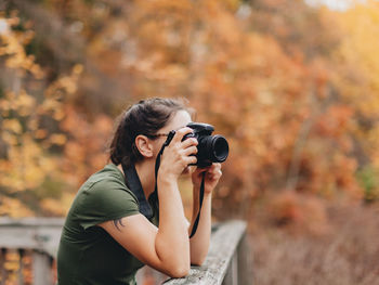 Young woman photographing during autumn