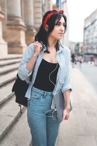 Young woman holding laptop standing in city