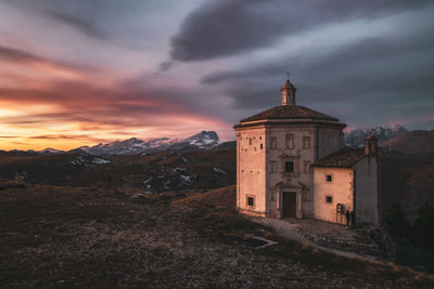 Old chapel on mountain against cloudy sky during sunset