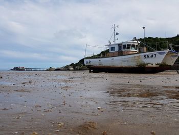 Ship moored on beach against sky