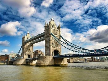 Bridge over river against cloudy sky