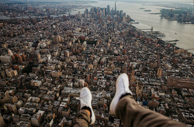 Low section of man sitting in helicopter over buildings in city