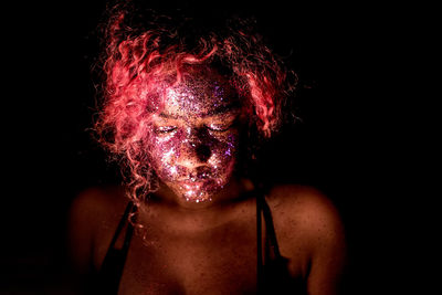 Close-up of woman with glitter make-up against black background