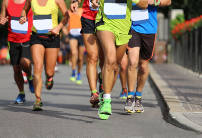 Low section of male athletes running marathon on road