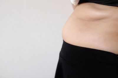 Midsection of woman standing against white background