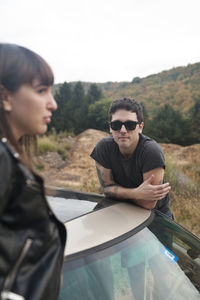 Young man looking at camera while standing by car