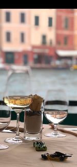 Wine glasses on table in restaurant against buildings in city